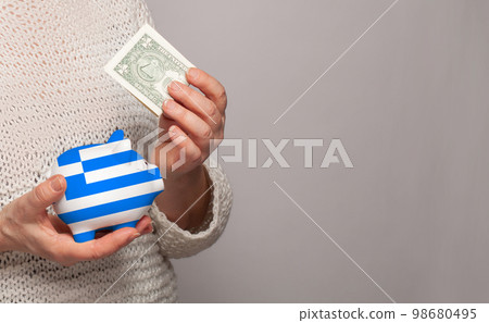 Flag of Greece on money bank in Greek woman hands. 98680495