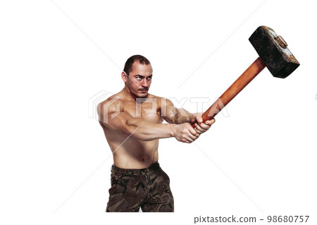 Strong brutal man with naked torso who strikes with sledgehammer while isolated on white background Strong brutal man with naked torso who strikes with sledgehammer while isolated on white background 98680757