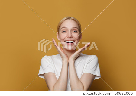 Portrait of happy attractive woman laughing and looking at camera against yellow studio 98681009