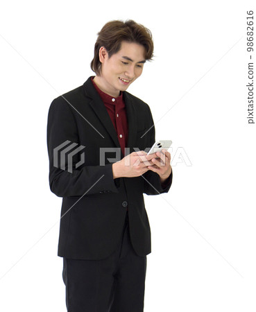 Young asian businessman in black suit reading text message on mobile phone. Portrait on white background with studio light. Young asian businessman in black suit reading text message on mobile phone. Portrait on white background with studio light. 98682616