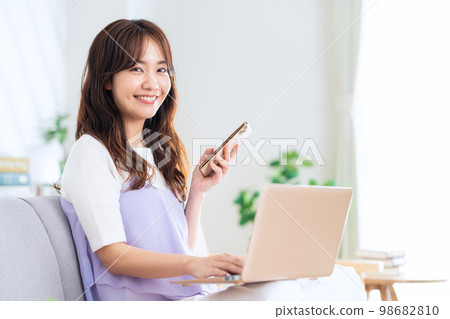 Living room, computer, smartphone, telework, female 98682810