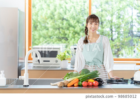 站立在廚房裡的一個微笑的少婦 98685012