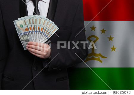 100 US dollar bills money banknotes in hand against flag of Tajikistan background 98685073