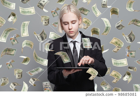 Concept photo of a businesswoman with tablet standing under money rain. 98685081