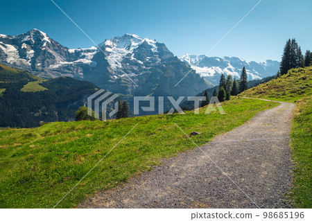 Hiking trail on the slope and high mountains in background Hiking trail on the slope and high mountains in background 98685196