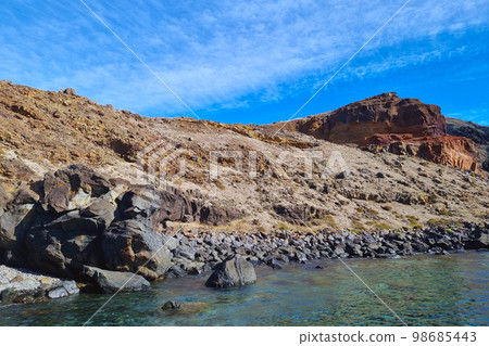 Red land and rocks on the island of Madeira. The rocks are washed by water. Red land and rocks on the island of Madeira. The rocks are washed by water. 98685443
