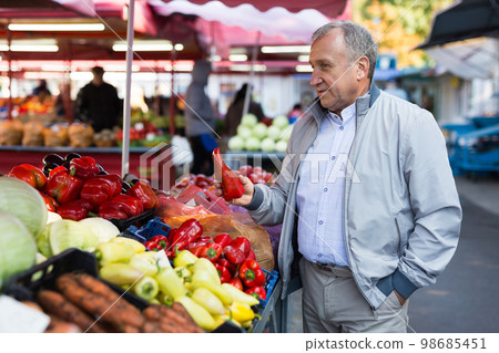 Middle aged man buying peppers Middle aged man buying peppers 98685451