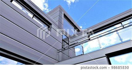 Bottom view of the stunning facade of a country house against a blue sky. Futuristic metal panels make the exterior of the property more inviting. 3d rendering. 98685830