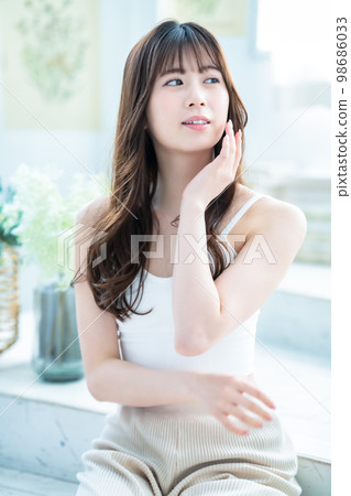 A young woman feels her skin become more moisturized A young woman feels her skin become more moisturized 98686033
