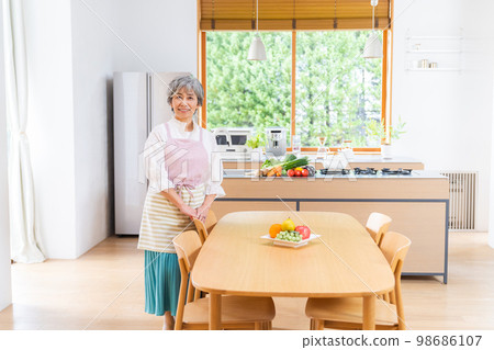 Smiling senior woman standing in the kitchen Smiling senior woman standing in the kitchen 98686107