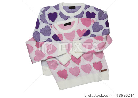 Two sweaters with a pattern of pink and lilac hearts, the sweaters lie one on top of the other, isolate 98686214