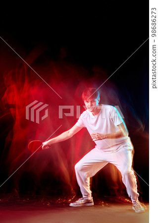 young man playing table tennis in mixed neon light 98686273
