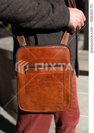 close-up photo of brown messanger leather bag on mans shoulder 98686570