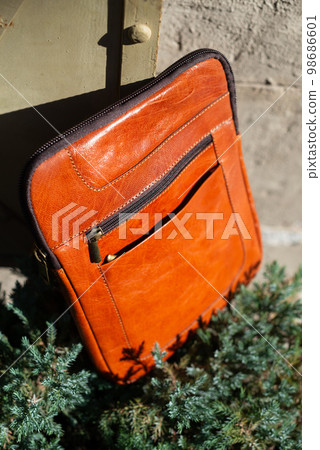 close-up photo of orange messanger leather bag. 98686601
