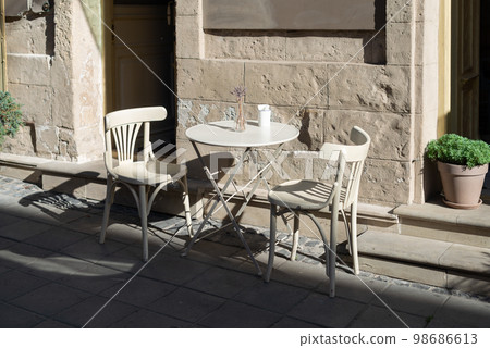 Lovely purple flowers on white rustic wooden outdoor furniture. Two chairs and table. street photo 98686613