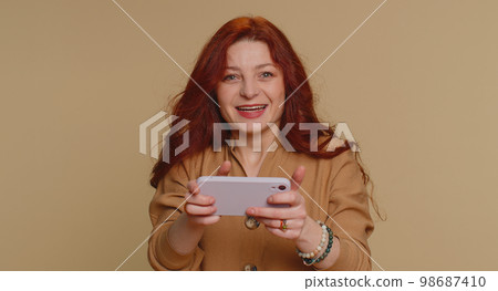 Worried funny addicted tourist girl enthusiastically playing drive racing video game on mobile phone 98687410