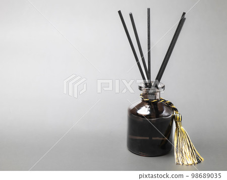 long black fragrant sticks one by one In a luxury opaque glass bottle with essential oils to spread the fragrance gray background There is a text area. long black fragrant sticks one by one In a luxury opaque glass bottle with essential oils to spread the fragrance gray background There is a text area. 98689035