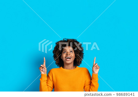 Excited african american young woman showing empty space above Excited african american young woman showing empty space above 98689141