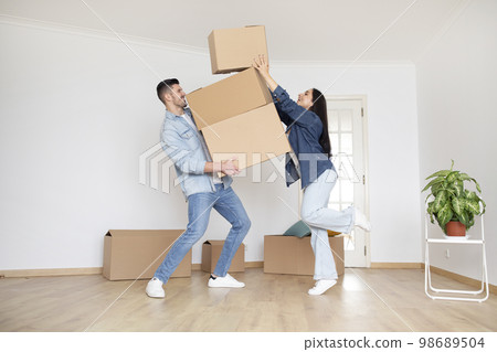 Relocation Day. Happy Young Spouses Carrying Cardboard Boxes While Moving, Relocation Day. Happy Young Spouses Carrying Cardboard Boxes While Moving, 98689504