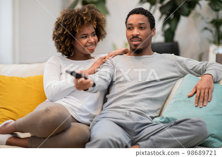 Black woman in love looking at her boyfriend watching TV 98689721