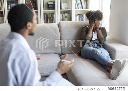 Black man psychologist have conversation with frustrated crying young woman Black man psychologist have conversation with frustrated crying young woman 98689755