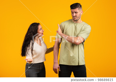 Angry dissatisfied young arab woman swears and yells at offended guy in casual, make stop sign with hand Angry dissatisfied young arab woman swears and yells at offended guy in casual, make stop sign with hand 98689815