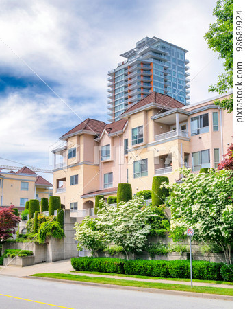 Italian style low-rise residential building with decorative trees in front 98689924