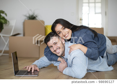 Happy Young Spouses Embracing And Using Laptop After Moving To Their New Home, Happy Young Spouses Embracing And Using Laptop After Moving To Their New Home, 98690127