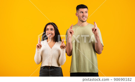 Pensive cheerful young arabic woman and guy in casual with fingers crossed, thinking, dreaming 98690182