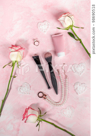 Arrangement of pink quartz stone Guasha scraper, roller massager, roses, jewelry, cosmetic tube, brushes on pink. Female beauty care. Valentine's day woman presents. Top view, flat lay Vertical format 98690518