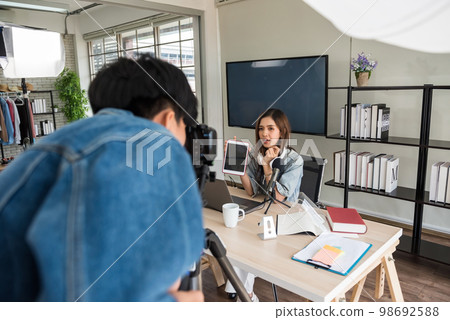 Videographer recording footage of female influencer in studio 98692588