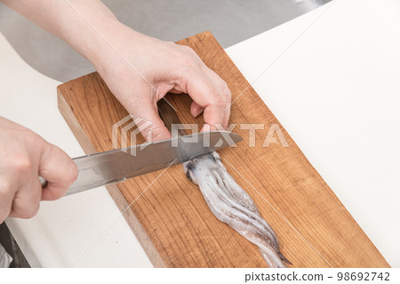 [A middle-aged housewife cuts a squid, preparing to remove her eyes] 98692742