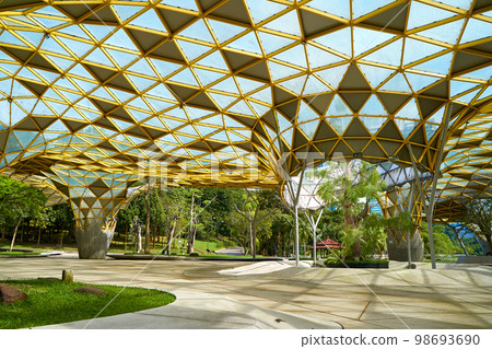 A futuristically designed sunshade with holes for trees in a city recreation park 98693690