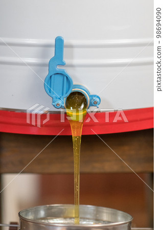 Drop of bee honey drip from hexagonal honeycombs Drop of bee honey drip from hexagonal honeycombs 98694090