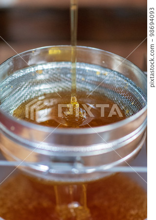 Drop of bee honey drip from hexagonal honeycombs Drop of bee honey drip from hexagonal honeycombs 98694093