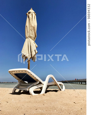 Stylish lounger in yellow sand to sun sunbed on beach in summer under open sky 98694332
