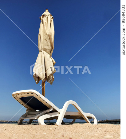 Stylish lounger in yellow sand to sun sunbed on beach in summer under open sky 98694333
