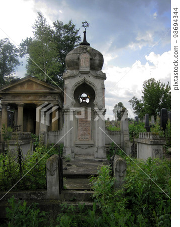 Old abandoned Jewish cemetery with stone graves between trees Old abandoned Jewish cemetery with stone graves between trees 98694344