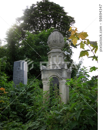 Old abandoned Jewish cemetery with stone graves between trees Old abandoned Jewish cemetery with stone graves between trees 98694347