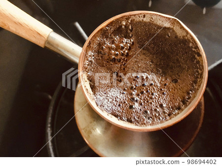 Barista preparing hot tasty drink from copper turk Barista preparing hot tasty drink from copper turk 98694402