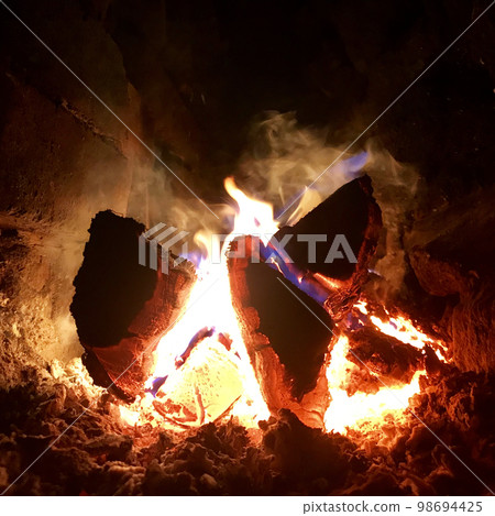 Beautiful flame brown wood dark black coal on bright yellow fire inside metal brazier 98694425