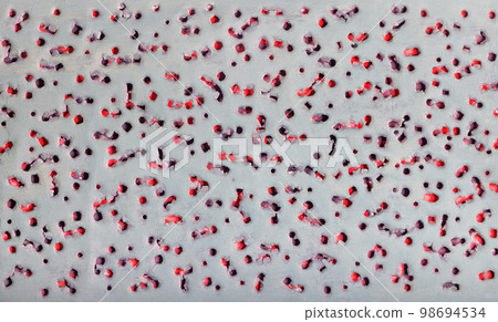 Abstract pattern texture with pierced ragged holes on a gray background on an underlay of red. 98694534