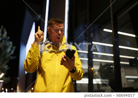 Inspired tourist looks at screen of his smartphone and finds solution to his problem. 98694857