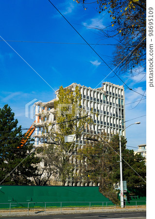 Demolition of the old building with sloopkraan against blue clouds sky. 98695109
