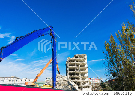 Demolition of the old building with sloopkraan against blue clouds sky. 98695110