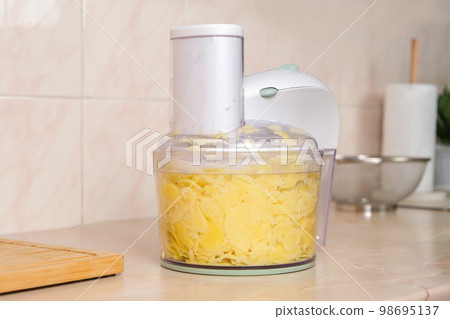 Potatoes cut into thin slices in food processor 98695137