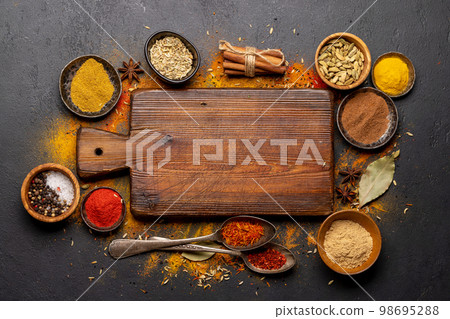 Empty cutting board over various spices 98695288