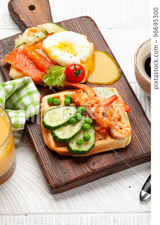 Breakfast waffles with fried eggs, salmon, cucumber and prawns 98695300