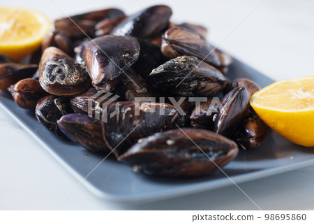Close up of a plate with freshly coocked mussels on dining table. High quality photo Close up of a plate with freshly coocked mussels on dining table. High quality photo 98695860
