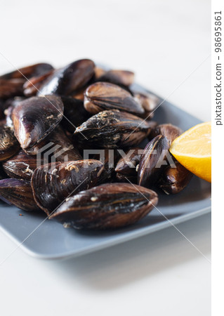 Close up of a plate with freshly coocked mussels on dining table. High quality photo Close up of a plate with freshly coocked mussels on dining table. High quality photo 98695861